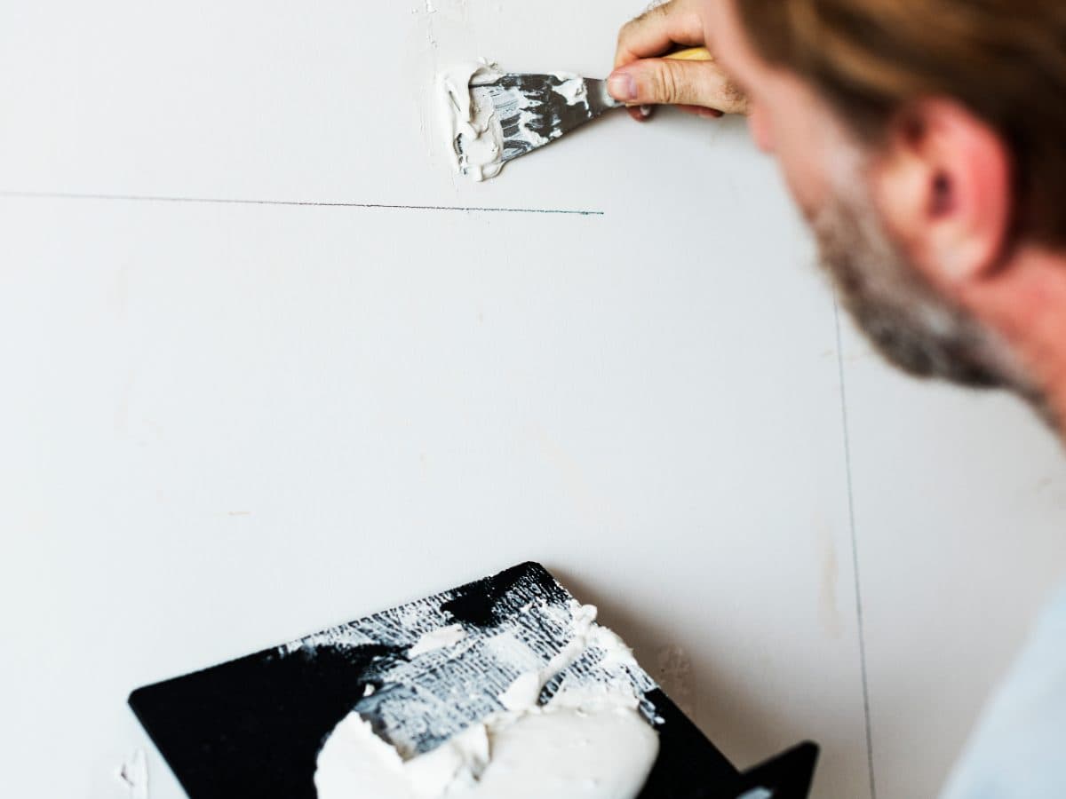 A Tasker repairing a wall in a customer's home